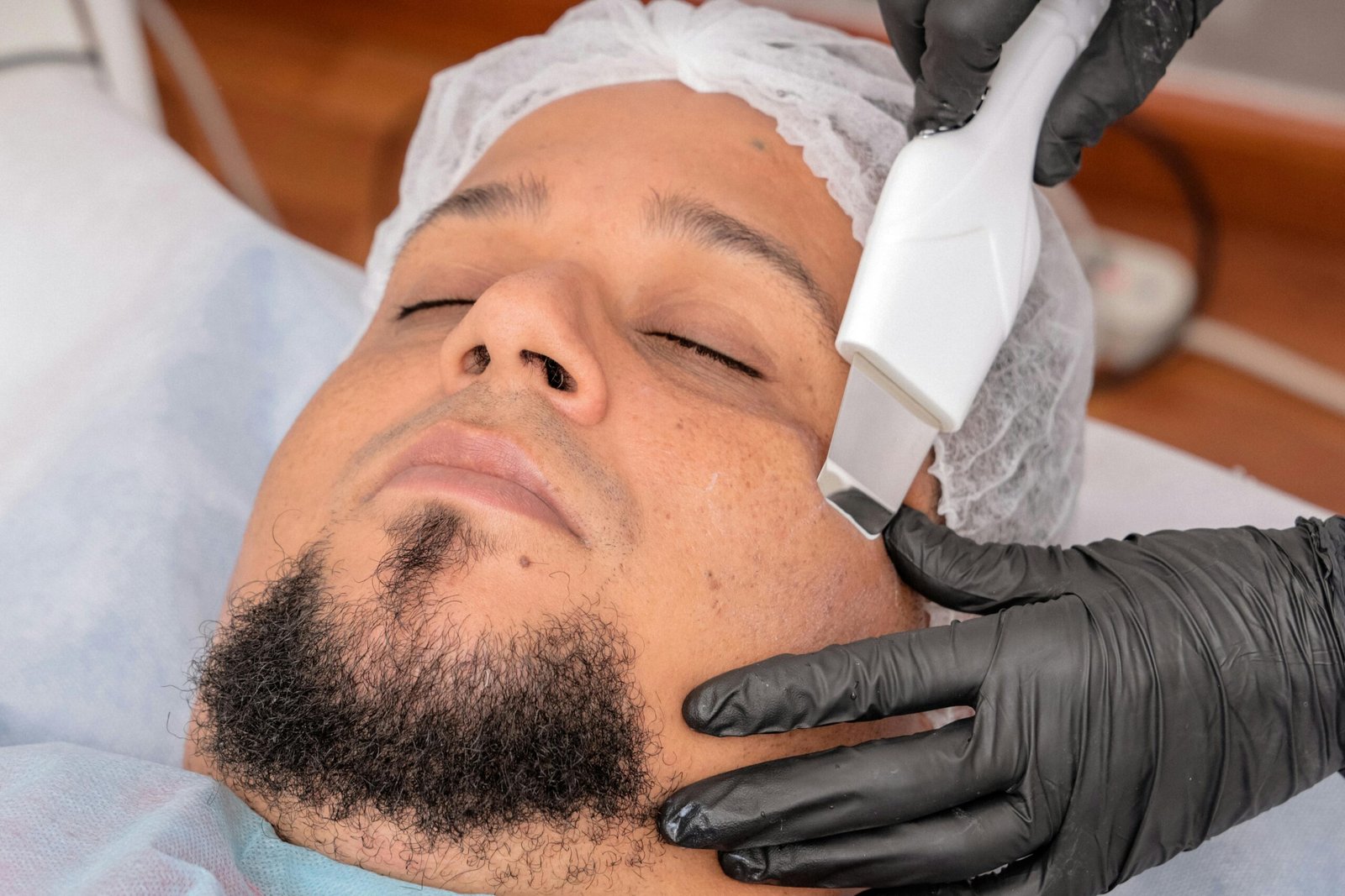 A man undergoing a facial treatment with advanced cosmetology equipment.